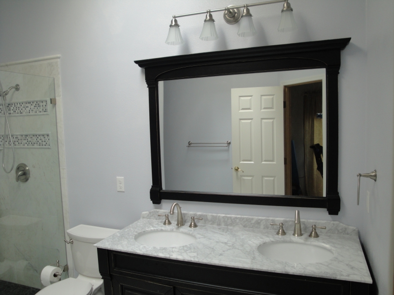 Dark-framed mirror above a white bathroom vanity and countertop