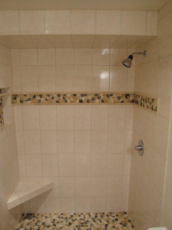 Custom tiled shower with river rock floor and built-in bench